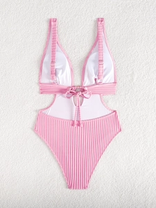 Detail of pink ribbed swimsuit with side cut-outs and metal ring on white plush rug