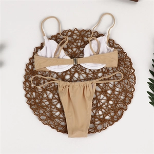 Flat lay of beige bikini set with underwire top and thong bottoms on woven mat