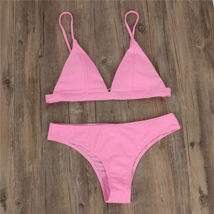 Flat lay of pink two-piece bikini featuring thin straps and high-cut bottoms on wood background
