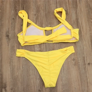 Detailed flat lay of a bright neon yellow two-piece bikini set on a wooden surface