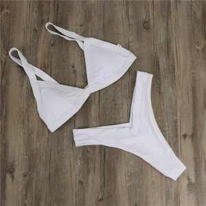 Detail view of white high-waist bikini set with M size label on textured wood background