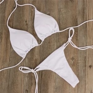 Flachbild von weißem Triangel-Bikini-Top und Schnürhose auf einem Holzhintergrund-Design