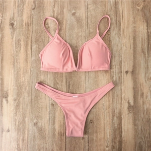 Ensemble bikini rose côtelé avec détail d'anneau métallique sur fond bois clair