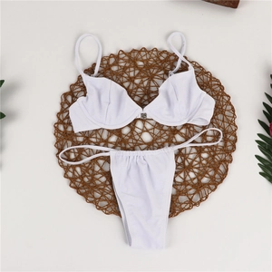 Flat lay of white ribbed bikini with underwire support on a natural woven mat