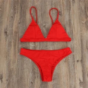 Flat lay of a red two-piece halter bikini on a wooden surface with a minimalist design