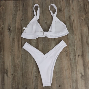 Flat lay detail of white two-piece bikini set with high waist bottom on wood background
