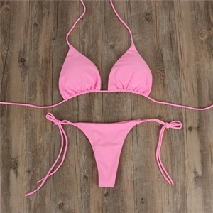 Flatlay-Detail des rosa Bikini-Sets mit Triangel-Cups und seitlichen Bändern auf Holz