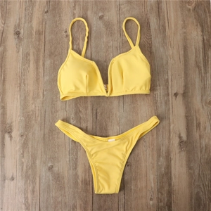 Ensemble bikini jaune côtelé posé à plat avec haut en V sur une surface en bois sombre
