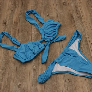 Flat lay of bright blue two-piece bikini featuring ruched details and knot front