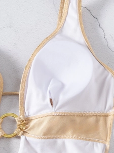 Detailed close-up of white mesh lining and gold metal ring on luxury one-piece swimsuit