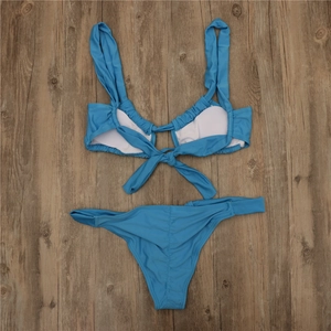 Sky blue string bikini set with tie-back top on a dark brown wooden floor background