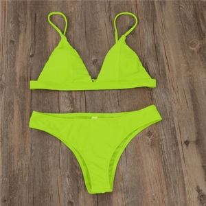 Flat lay of neon green triangle bikini set with thin straps on dark wood background