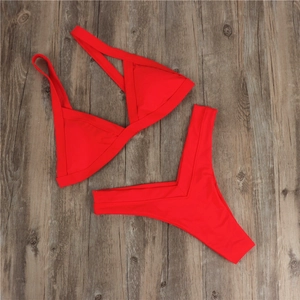 Detailed flat lay of red two-piece bikini with cross shoulder straps on wood floor