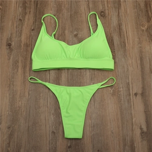 Detailed flat lay of neon green two-piece bikini set on minimalist dark wood texture