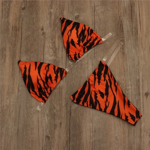 Detailed view of orange tiger print bikini with transparent PVC shoulder straps on wood