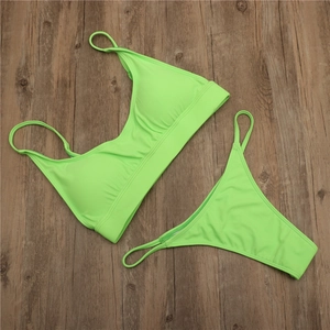 Flat lay view of neon green two-piece bikini set on a rustic dark wood background