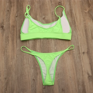 Detailed flat lay of neon green bikini set with removable white chest pads on wood surface