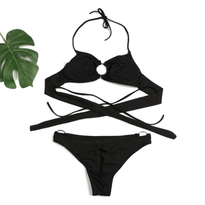 Detailed flat lay of black halter bikini with metal ring accents and waist ties