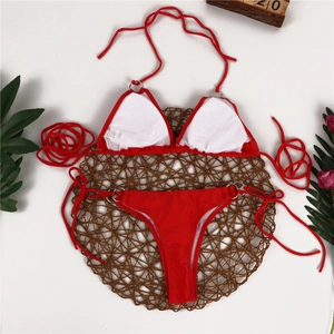 Flat lay of red bikini set on woven mat with tropical plants for vacation vibes