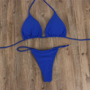 Flat lay of royal blue triangle bikini set with side-tie bottoms on wooden texture