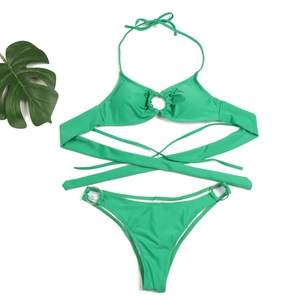 Flat lay of emerald green bikini set with silver metal rings and lush green leaf detail
