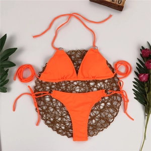 Flat lay of neon orange bikini set with silver rings and tropical decorative accessories