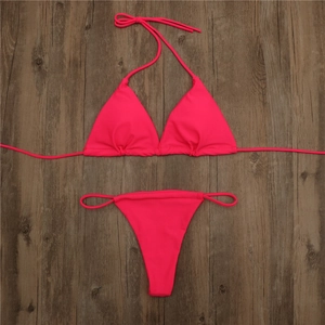 Flat lay of a hot pink triangle halter bikini set on a dark wood background