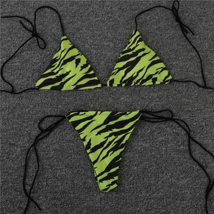 Vue à plat détaillée d'un bikini imprimé zèbre vert fluo sur un fond de tapis texturé