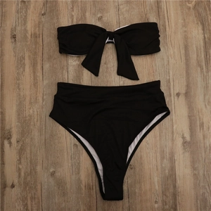 Bikini noir côtelé à taille haute avec nœud frontal sur un fond de bois texturé
