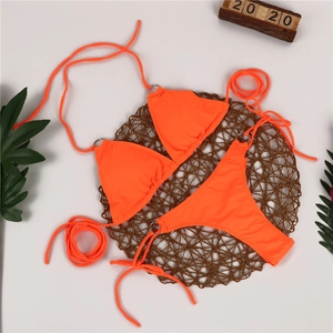 Detailed flat lay of bright orange bikini set with metal rings and tropical leaf decor