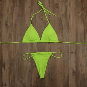 Flat lay of a neon green triangle bikini set with side ties on a dark wooden background