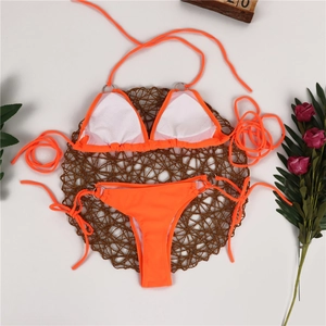 Flat lay of neon orange bikini set with metallic ring accents and side-tie bottoms