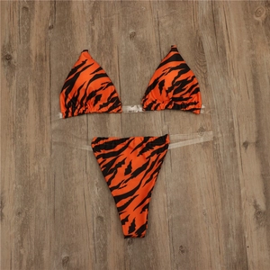 Two-piece bikini set with vibrant tiger print and transparent straps on wooden background