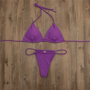 Flat lay of a vibrant purple two-piece bikini with adjustable ties on a wooden surface