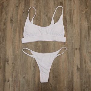 Detailed top view of a white two-piece bikini set on dark vintage wood background