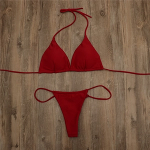 Flat lay of red triangle bikini set with adjustable straps on a dark wooden texture