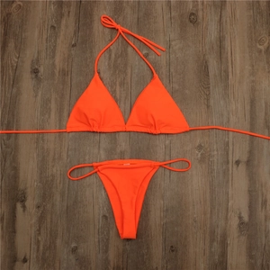 Detailed flat lay of neon orange triangle bikini top and tie-side thong on wood surface