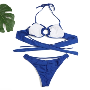 Detail of royal blue bikini set with metal rings, ruched fabric, and wrap ties on white