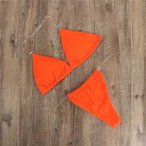 Detail of orange bikini set with transparent silicone straps on wooden background