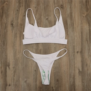 Detailed flat lay of a white two-piece bikini with sanitary hygiene sticker on wood
