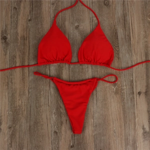 Detailed flat lay of red lace-up bikini set on a vintage dark wood textured background