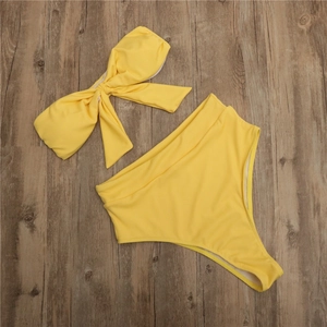 Détail du tissu côtelé jaune du bikini avec nœud sur le haut et culotte à taille haute