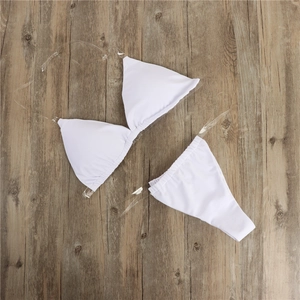 Detailed flat lay of a white bikini with transparent straps on a wooden surface
