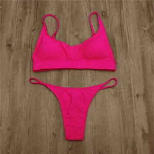 Flat lay of neon pink strapless bikini set with ribbed texture on dark wood background