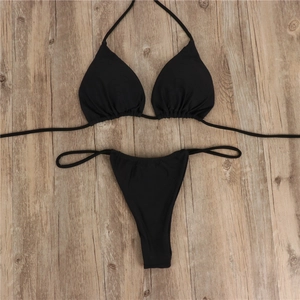 Flat lay of a classic black halter bikini set with string ties on light wood background
