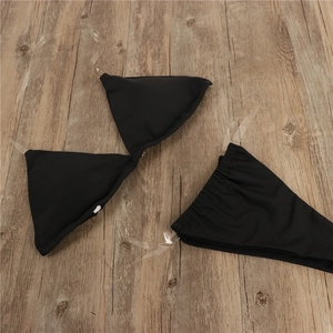 Flat lay of black bikini set featuring transparent silicone straps and matte fabric