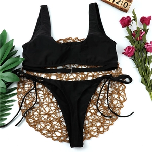 Detail of black bikini set featuring metal heart buckle and side tie strings on white background