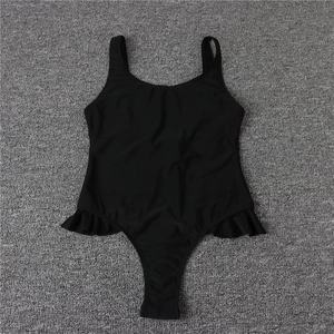 Flat lay of a black one-piece swimsuit featuring wide straps and ruffled hip details