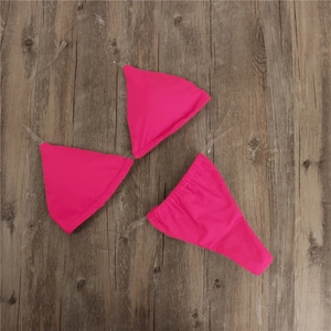 Detailed view of pink bikini set with transparent straps laid on wooden background