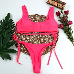 Neon pink bikini set with heart metal buckle on a summer beach flat lay background